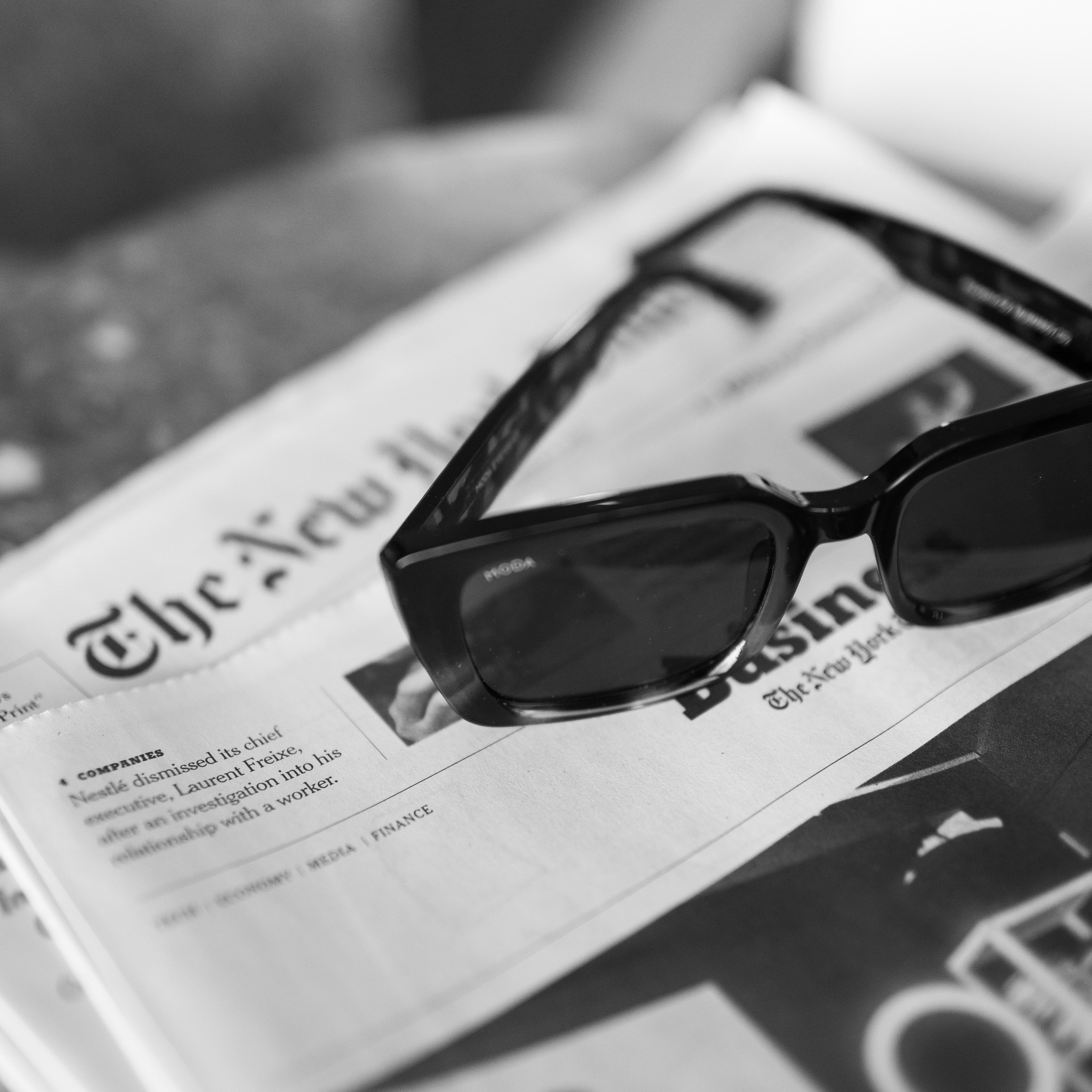 Sunglasses on top of a newspaper with blurred background